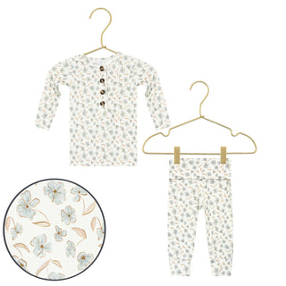 Lou Lou and Company Top and Bottoms - Faye
A two-piece baby outfit set consisting of a long-sleeve henley shirt and matching pants, both featuring a delicate floral print on an off-white background. The set is displayed on gold-colored hangers, with a circular zoom-in detail of the floral pattern in the bottom-left corner.