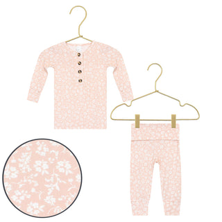 Lou Lou and Company Top and Bottoms - Louise
A baby two-piece pajama set featuring a long-sleeve henley top and matching pants, both in a light pink color with a white floral pattern. The top has three brown buttons on the chest.