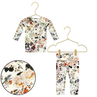 Lou Lou and Company Top and Bottoms - Nellie
A toddler girl's two-piece floral print outfit consisting of a long-sleeve top and matching leggings, displayed on gold hangers against a white background, with a circular inset showing a close-up of the fabric pattern.