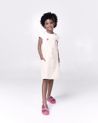 Mini Melissa Cozy Slide Kids - Pink / Glitter
Young girl wearing a white dress with pink buttons on a white background