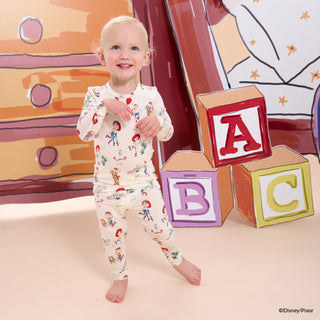 Magnetic Me x Disney L/S Modal Pajama Set - Toy Story Woody & Friends
Child in pajamas with cartoon characters standing next to colorful ABC blocks in a playful setting.