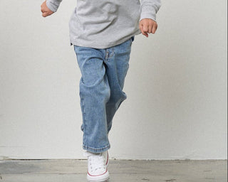 Little Bipsy Straight Leg Jean - Light Wash
Person wearing blue jeans and white sneakers on a plain background