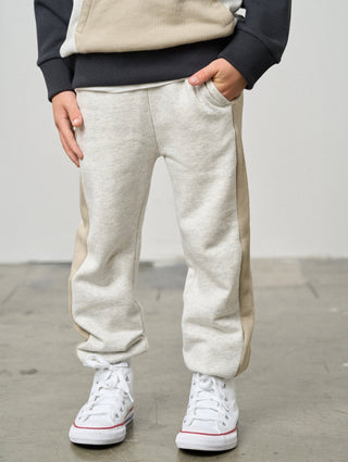 Little Bipsy Side Stripe Jogger - Stone Grey
Person wearing beige and navy sweatpants with white high-top sneakers on a plain background