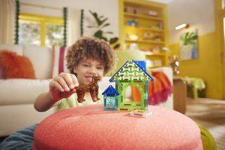 Magna-Tiles Dog House™ 13-Piece Set
Child playing with toy house and animal figurine in a colorful living room.