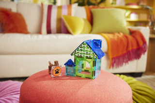 Magna-Tiles Dog House™ 13-Piece Set
Colorful toy house and dog figurine on a pink ottoman with a patterned sofa in the background
