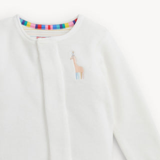 Magnetic Me Embroidery Cream Velour Footie - Giraffe
A close-up of a white long-sleeve baby top or cardigan with a colorful striped inner collar and a small embroidered giraffe on the chest.