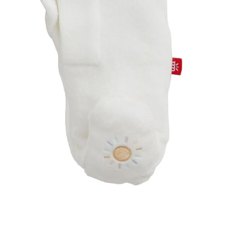Magnetic Me Embroidery Cream Velour Footie - Giraffe
A close-up of a white plush bootie or sock with a small embroidered sun motif on the front and a small red fabric tag near the side.