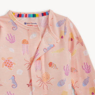 Magnetic Me Modal Footie - Deep Chic Pink 
Baby onesie with sea creature pattern and rainbow trim on a white background