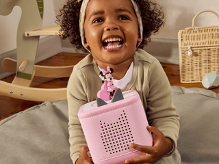 Tonies Character - Disney: Minnie Mouse Clubhouse
Child holding a pink toy with a Minnie Mouse character, sitting on a bed in a bedroom setting.