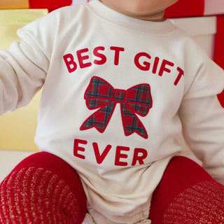 Sweet Wink Christmas long sleeve romper with shiny red velvet bow, pearl headband, and festive tartan pattern on model.