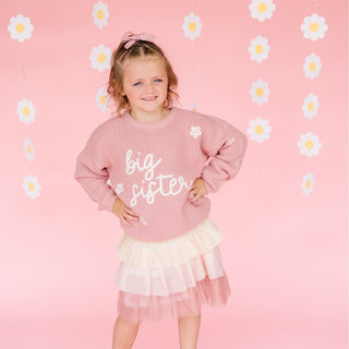 Sweet Wink Big Sister Knit Sweater
Child wearing a pink 'big sister' shirt with a floral background