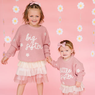 Sweet Wink Big Sister Knit Sweater
Two young girls in matching outfits with 'big sister' and 'little sister' text on a pink floral background.