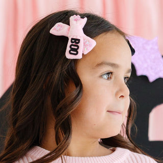 Sweet Wink Boo Bows Halloween Clip Set
Young girl wearing a pink hair bow with 'BOO' on it against a pink background