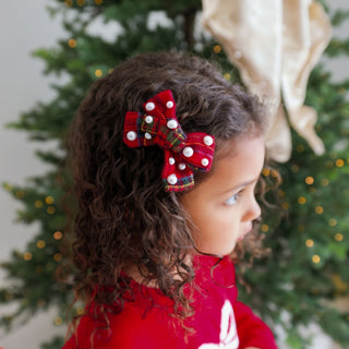 Sweet Wink Christmas tartan pearl hair clip worn in model's hair, featuring a festive tartan bow with pearl accents.