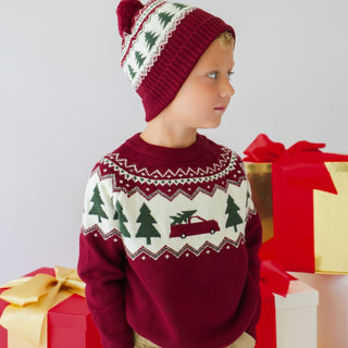 Model wearing Sweet Wink Christmas Truck Fair Isle sweater in khaki, paired with joggers and a Christmas tree fair isle beanie.
