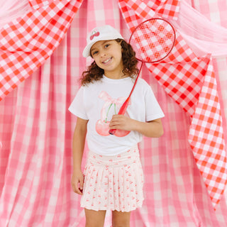 Model wearing Sweet Wink Cherry Cute athletic skort with cherry sequin patch, paired with a matching cherry short-sleeve T-shirt and baseball hat.