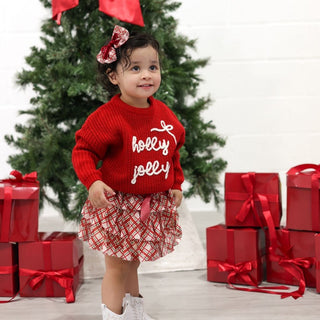 Sweet Wink Holly Jolly Bow Christmas Knit Sweater - Kids
Child wearing a red sweater with 'holly jolly' text, standing in front of a Christmas tree and presents.
