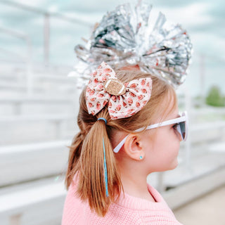 Sweet Wink Football Cutie Tulle Bow Clip Child with large silver hair bow and pink floral headband outdoors