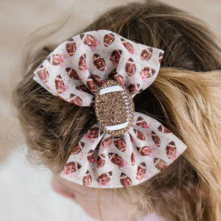 Sweet Wink Football Cutie Tulle Bow Clip Hair bow with football pattern and rhinestone center on a child's head