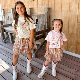 Sweet Wink Cowgirl Cutie Short Sleeve T-Shirt - Ballet 
Two young girls in matching outfits with cowboy boots standing on a wooden deck.