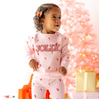 Model wearing Sweet Wink Jolly Pearl Patch Candy Cane Christmas sweatshirt and flare leggings 2-piece set for holiday style.