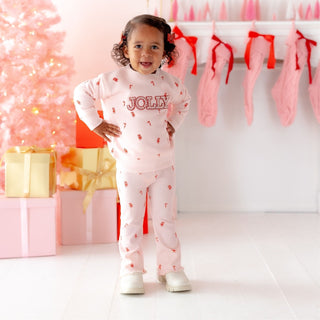 Model wearing Sweet Wink Jolly Pearl Patch Candy Cane Christmas sweatshirt and flare leggings set, festive holiday 2-piece outfit.