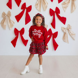 Model wearing Sweet Wink Merry Bow Christmas Sweater with festive holiday design and colorful patterns.