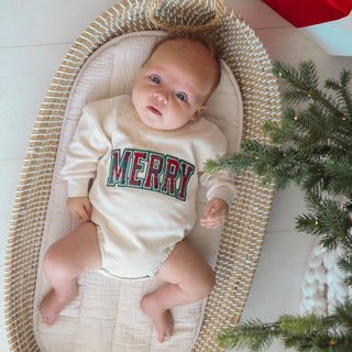 Model wearing a Sweet Wink Merry Tartan Patch Christmas long sleeve sweater romper with festive tartan patches and cozy knit fabric.