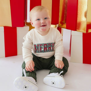 Sweet Wink Merry Tartan Patch Christmas long sleeve sweater romper on a model, featuring festive tartan patches and cozy forest corduroy fabric.