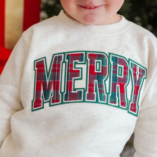 Model wearing Sweet Wink Merry Tartan Patch Christmas sweatshirt with festive tartan design and cozy fit.