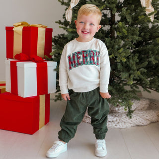 Model wearing Sweet Wink Merry Tartan Patch Christmas sweatshirt, featuring festive tartan patches on a cozy sweater.