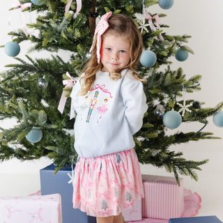 Model wearing Sweet Wink Nutcracker embroidered Christmas sweater featuring festive Nutcracker and trellis embroidery.