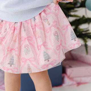 Model wearing Sweet Wink Nutcracker Trellis Christmas tutu skirt with embroidered nutcracker design and festive gemstone clip.