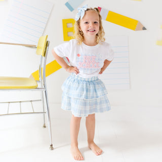 Sweet Wink Preschool Pearl Patch Short Sleeve T-Shirt
Young girl in a 'PRE SCHOOL' t-shirt and checkered skirt standing in front of a colorful wall.