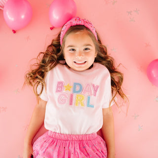 Sweet Wink Raspberry Rhinestone Headband
Young girl wearing a 'B-Day Girl' shirt with pink balloons on a pink background