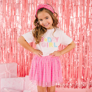 Sweet Wink Raspberry Rhinestone Tutu Skirt
Young girl wearing a 'Baby Girl' t-shirt and pink skirt with a pink sequin curtain background.
