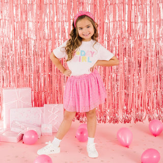 Sweet Wink Raspberry Rhinestone Tutu Skirt
Young girl in a pink and white outfit with 'Bday Girl' shirt, standing in front of a pink tinsel curtain.