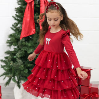 Sweet Wink Christmas Pearl Long Sleeve Tutu Dress
Young girl in a red dress with white polka dots standing next to a Christmas tree and presents.
