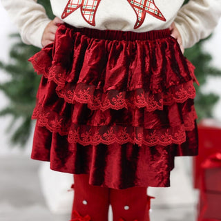 Sweet Wink Ruby Red Velvet Tiered Christmas Skirt
Child wearing a red skirt with lace details and a white sweater with red patterns, standing against a blurred green background.