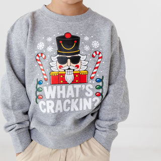 Model wearing Sweet Wink What's Crackin Christmas sweatshirt in khaki, showcasing the festive holiday sweater design.