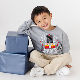 Model wearing Sweet Wink What's Crackin Christmas sweatshirt in khaki, featuring festive holiday graphic on cozy sweater.