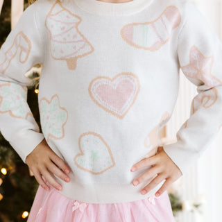 Model wearing Sweet Wink Christmas Cookies sweater in blush with bows, paired with a tutu skirt for festive holiday style.