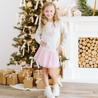 Model wearing a blush Christmas cookies sweater by Sweet Wink, paired with a tutu skirt and decorative bows.