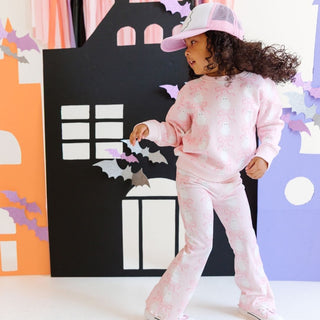Sweet Wink Coquette Ghost Halloween Sweatshirt & Flare Legging Set
Child wearing a pink tie-dye outfit with a matching cap in front of a Halloween-themed backdrop.