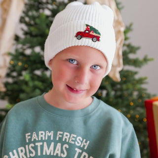 Model wearing Sweet Wink Christmas Tree patch sweatshirt in khaki, featuring festive holiday design with tree and truck details.