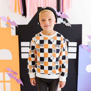 Sweet Wink Boo Checkered Halloween Sweatshirt - Natural Child wearing a Halloween-themed checkered sweater with ghosts and 'BOO' text, standing in front of a festive background.