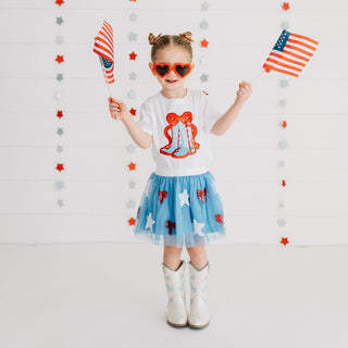 Model wearing Sweet Wink patriotic cowgirl patch short sleeve T-shirt with a red glitter bow and patriotic cutie tutu.