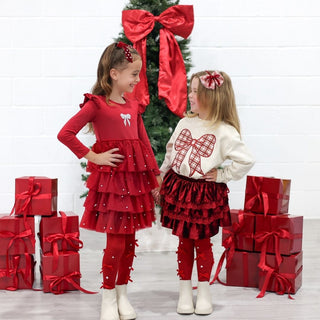 Sweet Wink Bedazzled Coquette Tights - Ruby RedTwo young girls in matching red and white outfits standing in front of a Christmas tree with red bows and presents.