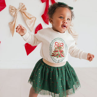 Sweet Wink sequin Christmas tree patch sweatshirt worn by a model, featuring long sleeves, festive embroidery, and holiday-themed details.