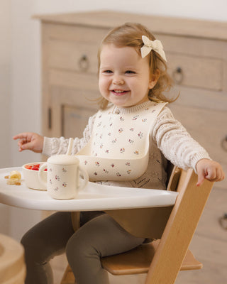 Mushie x Quincy Mae Heart Ditsy feeding set with plate, bowl, cup, and utensils for babies on a white background.